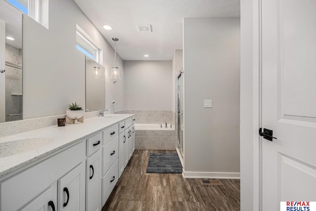 full bath with a sink, wood finished floors, a shower stall, and a bath