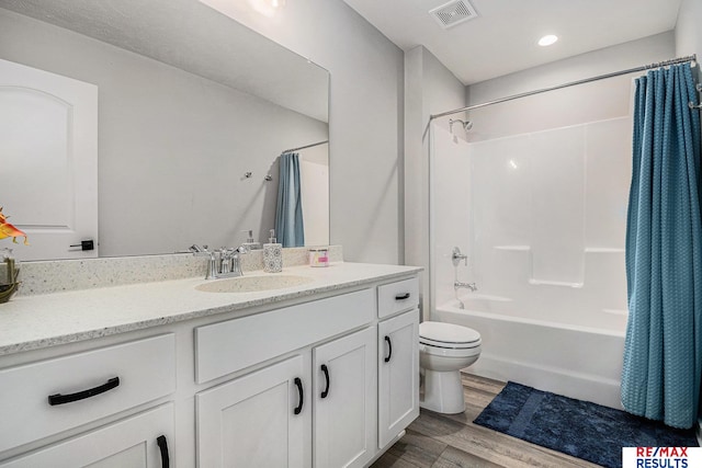 bathroom with visible vents, toilet, wood finished floors, shower / bath combination with curtain, and vanity