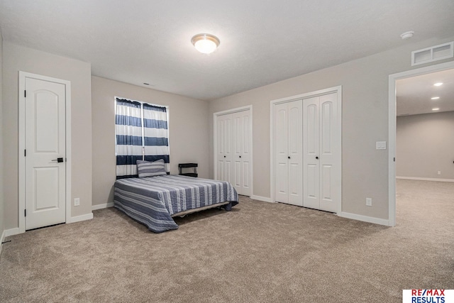 carpeted bedroom featuring visible vents, multiple closets, and baseboards