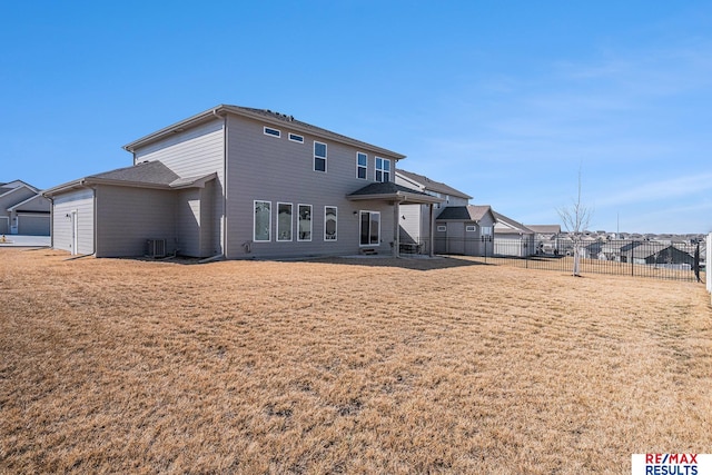 rear view of property with central AC unit, a lawn, a garage, and fence