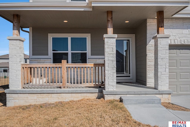 view of exterior entry with a garage and covered porch