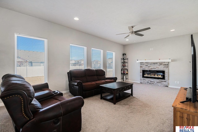 living area featuring a ceiling fan, baseboards, carpet floors, recessed lighting, and a stone fireplace