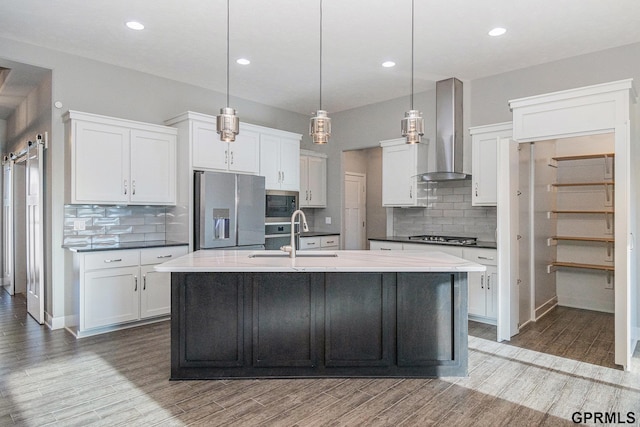 kitchen with a sink, wall chimney exhaust hood, wood finished floors, and stainless steel appliances