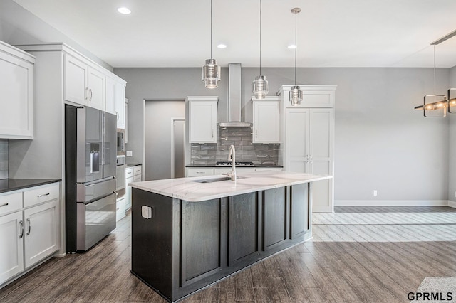 kitchen with tasteful backsplash, stainless steel refrigerator with ice dispenser, white cabinets, wall chimney exhaust hood, and dark wood-style flooring