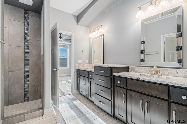 bathroom with vanity, a ceiling fan, baseboards, and tiled shower