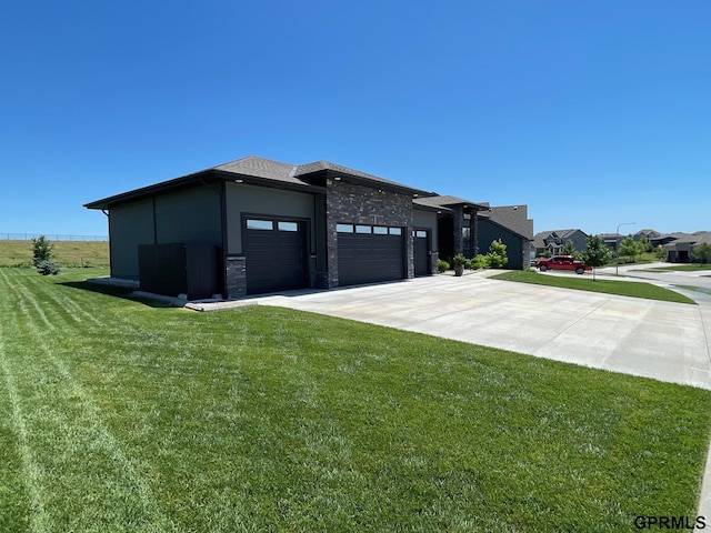 view of front of home with stone siding, a front yard, concrete driveway, and an attached garage