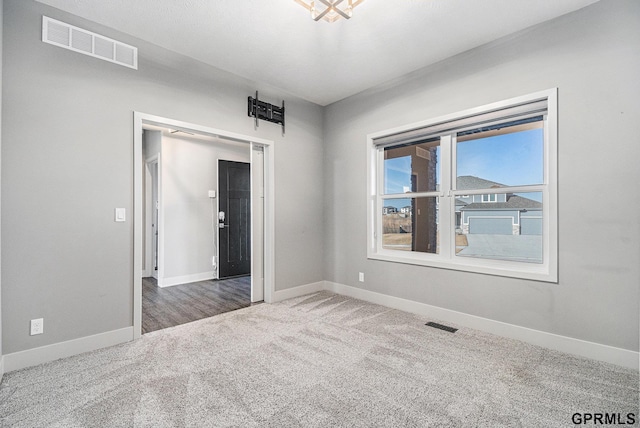 carpeted empty room with visible vents and baseboards