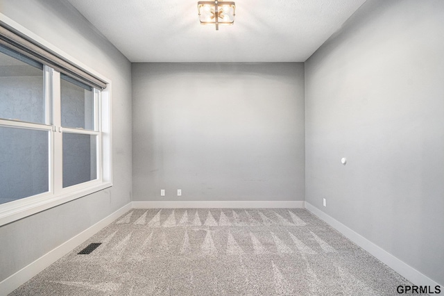 empty room with carpet, visible vents, and baseboards