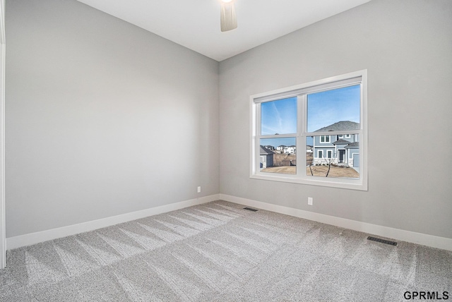 carpeted spare room with baseboards, visible vents, and ceiling fan