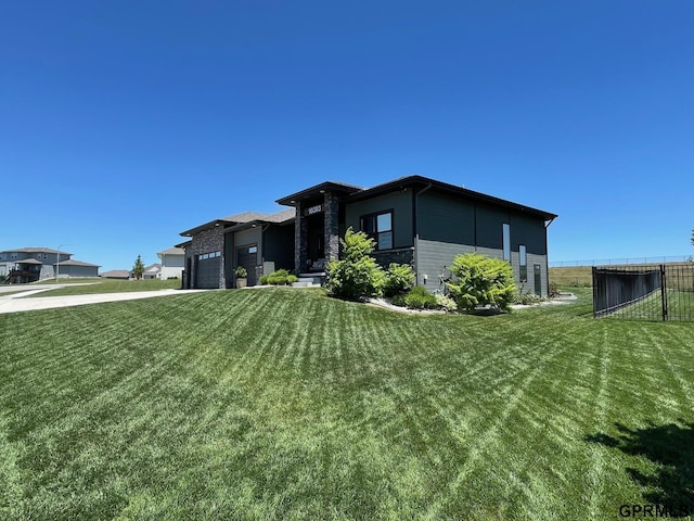 view of front of home with fence, a front lawn, concrete driveway, a garage, and stone siding