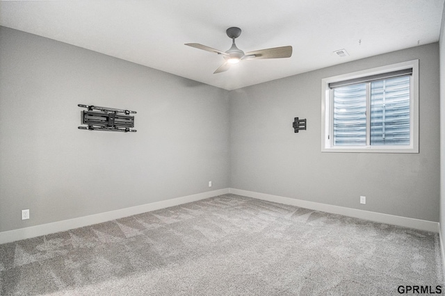 carpeted spare room with visible vents, a ceiling fan, and baseboards