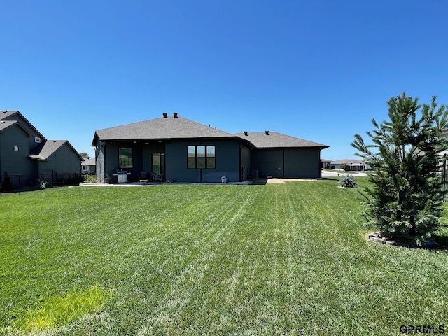 rear view of property featuring a lawn and fence