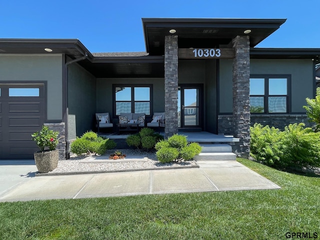 doorway to property featuring a porch, stucco siding, an outdoor hangout area, a garage, and stone siding