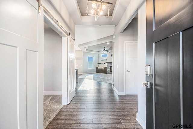 foyer entrance with baseboards, a raised ceiling, a barn door, and wood tiled floor