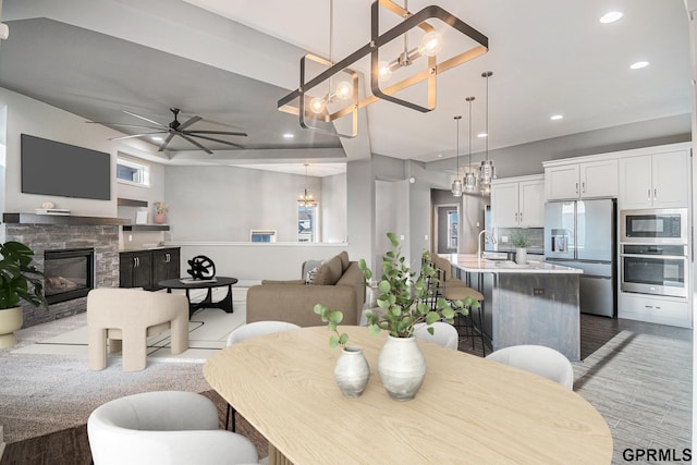 dining area featuring recessed lighting, light wood finished floors, a fireplace, and ceiling fan with notable chandelier