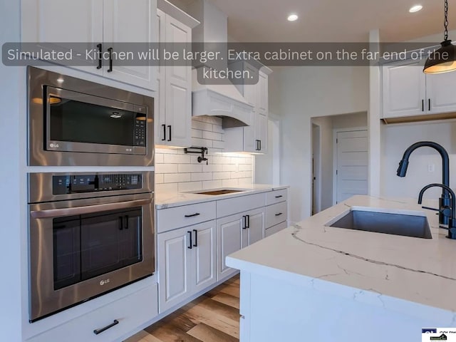 kitchen featuring a sink, backsplash, wood finished floors, stainless steel appliances, and white cabinets