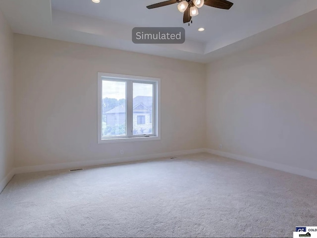 empty room featuring a tray ceiling, baseboards, ceiling fan, and carpet flooring