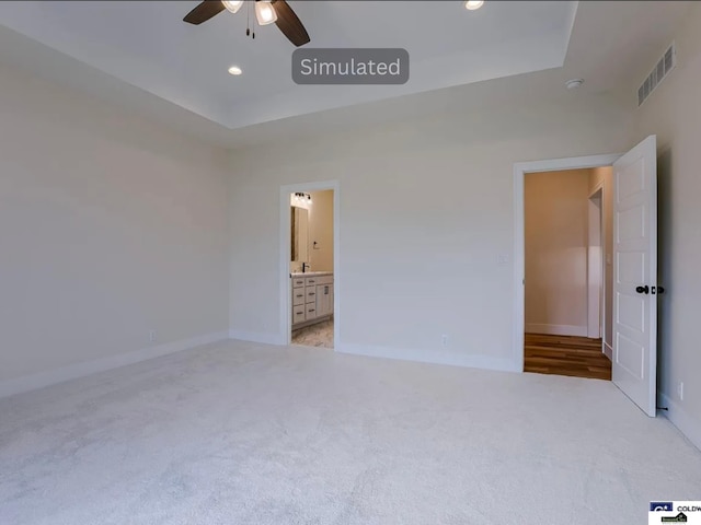 unfurnished bedroom with recessed lighting, visible vents, a raised ceiling, and carpet