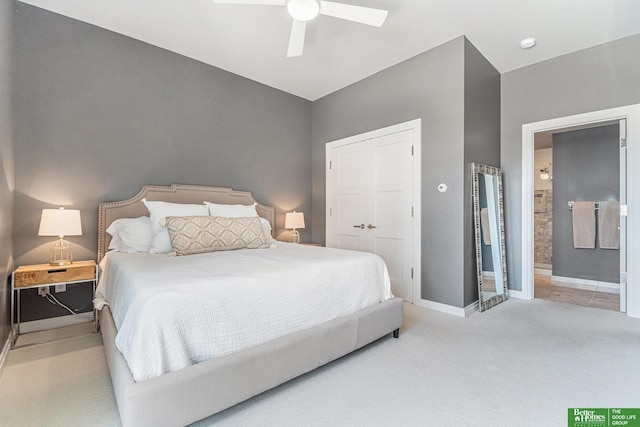 bedroom with baseboards, light carpet, ensuite bathroom, and a ceiling fan