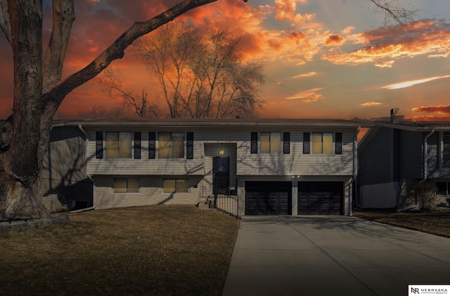 raised ranch featuring concrete driveway, a yard, and a garage