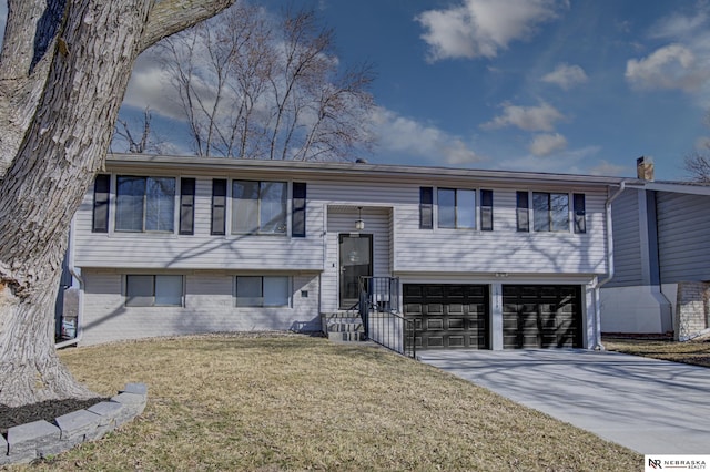 10230 Weir St, Ralston, NE 68127 - split foyer home with brick siding, an attached garage, concrete driveway, and a front yard