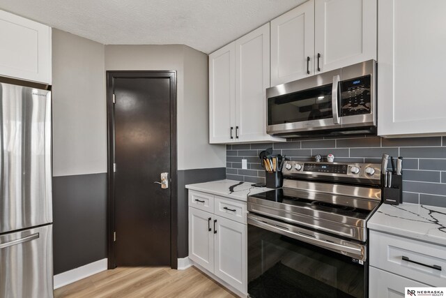 10230 Weir St, Ralston, NE 68127 - kitchen featuring light stone counters, stainless steel appliances, white cabinets, and light wood-style flooring