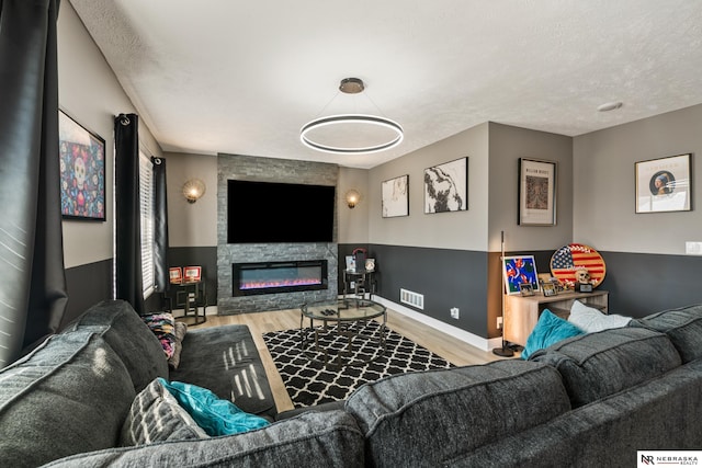 living area with visible vents, a fireplace, a textured ceiling, and wood finished floors