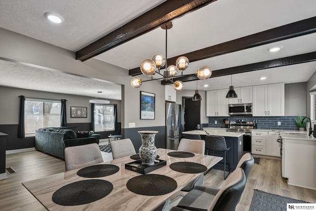 10230 Weir St, Ralston, NE 68127 - dining room with beam ceiling, light wood-style flooring, a textured ceiling, and an inviting chandelier