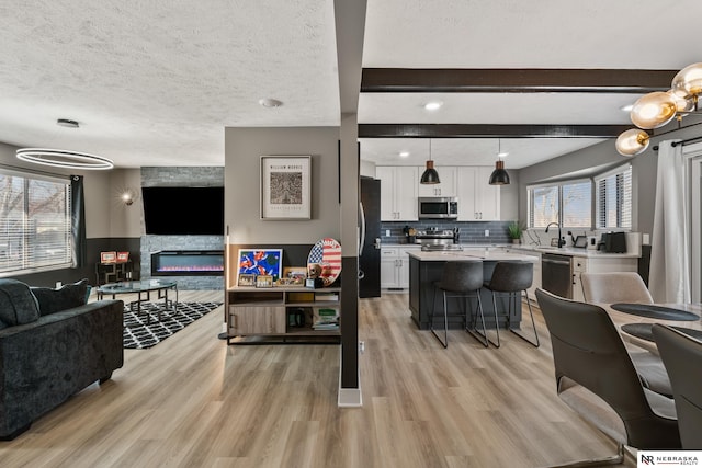 10230 Weir St, Ralston, NE 68127 - living room featuring beam ceiling, a fireplace, a textured ceiling, and light wood-style floors