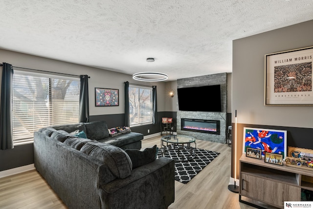 10230 Weir St, Ralston, NE 68127 - living room featuring light wood finished floors, a textured ceiling, a large fireplace, and baseboards