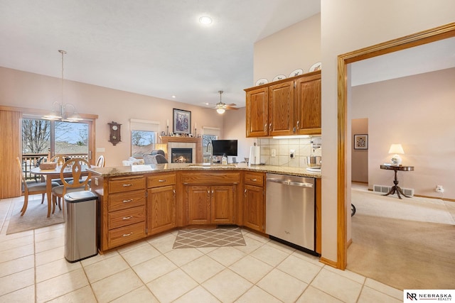 kitchen with ceiling fan with notable chandelier, a sink, tasteful backsplash, stainless steel dishwasher, and a peninsula