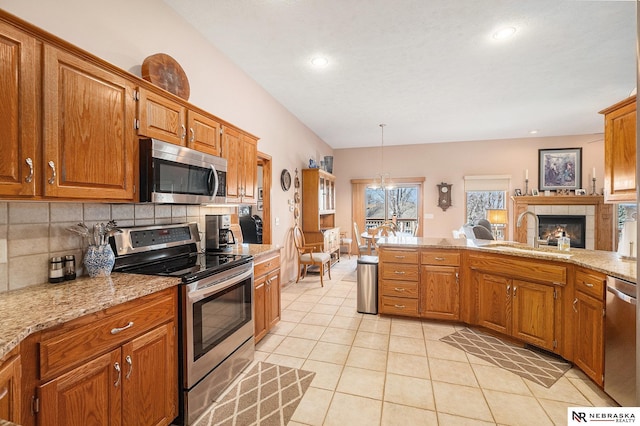 kitchen with light tile patterned floors, decorative backsplash, appliances with stainless steel finishes, a tile fireplace, and a sink