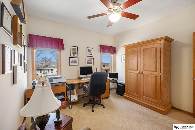 office space with light carpet, baseboards, and ceiling fan