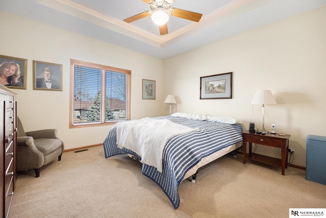 bedroom with visible vents, baseboards, a raised ceiling, light colored carpet, and ceiling fan