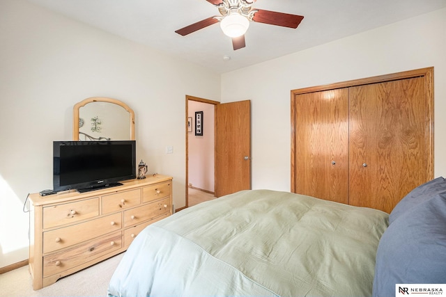 bedroom featuring a ceiling fan, light colored carpet, a closet, and baseboards