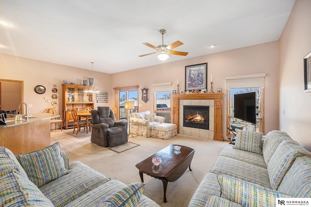 living area with light carpet, a fireplace, and a ceiling fan