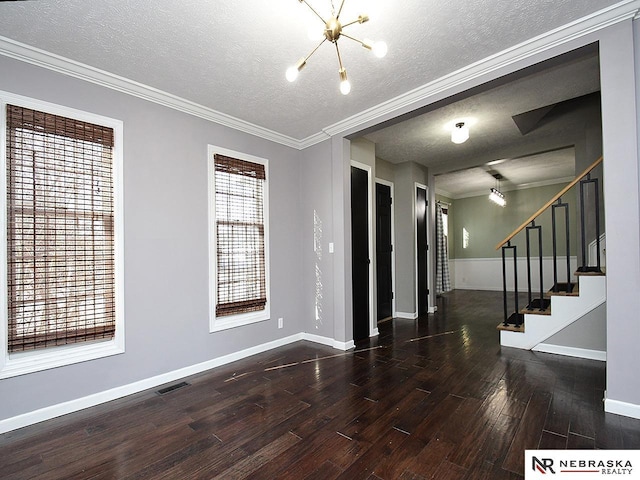 unfurnished room with visible vents, a notable chandelier, wood finished floors, baseboards, and stairs