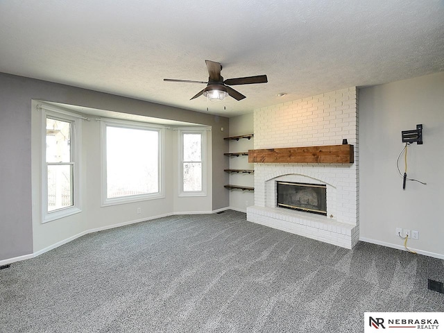 unfurnished living room with a wealth of natural light, a fireplace, ceiling fan, and dark colored carpet