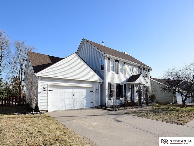 colonial home with an attached garage, concrete driveway, and fence