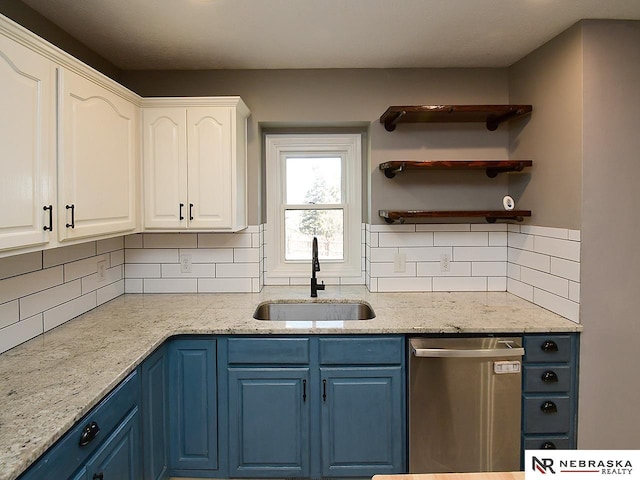 kitchen featuring a sink, blue cabinetry, stainless steel dishwasher, tasteful backsplash, and white cabinets