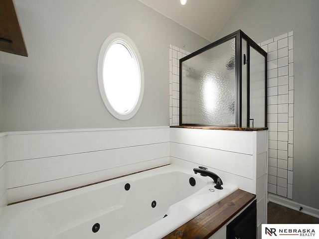 bathroom featuring vaulted ceiling, a jetted tub, and a stall shower