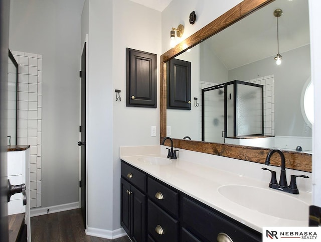 bathroom featuring double vanity, vaulted ceiling, a stall shower, and a sink