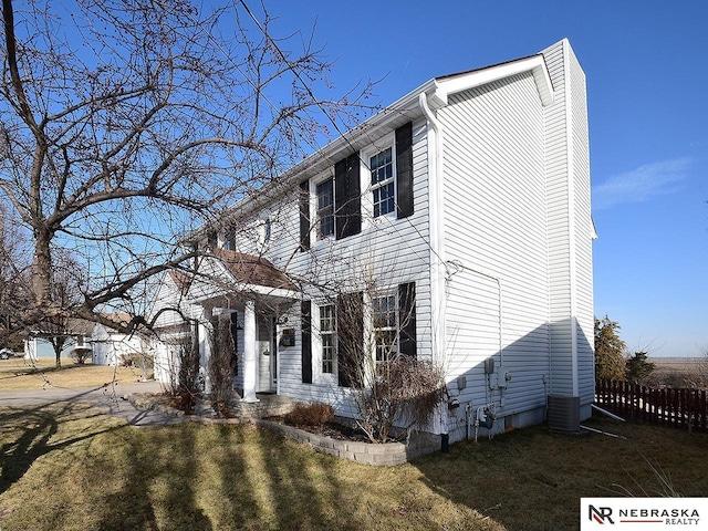 colonial-style house with a front lawn, cooling unit, and fence