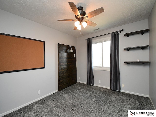 unfurnished bedroom with dark colored carpet, visible vents, baseboards, and a textured ceiling