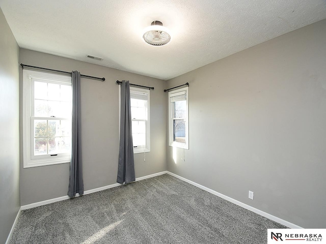 carpeted empty room featuring baseboards and a textured ceiling