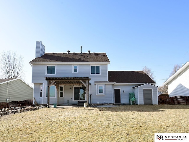 back of house featuring an outbuilding, a patio, fence, a yard, and a chimney