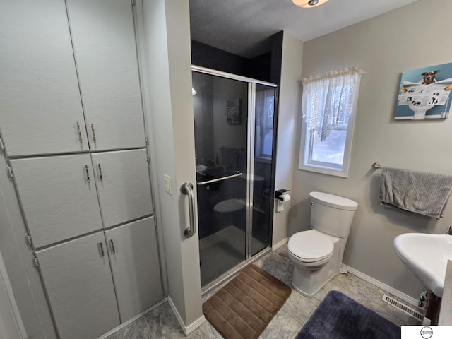 full bathroom with a shower stall, toilet, baseboards, and a sink