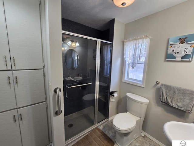 full bath with wood finished floors, baseboards, toilet, and a stall shower