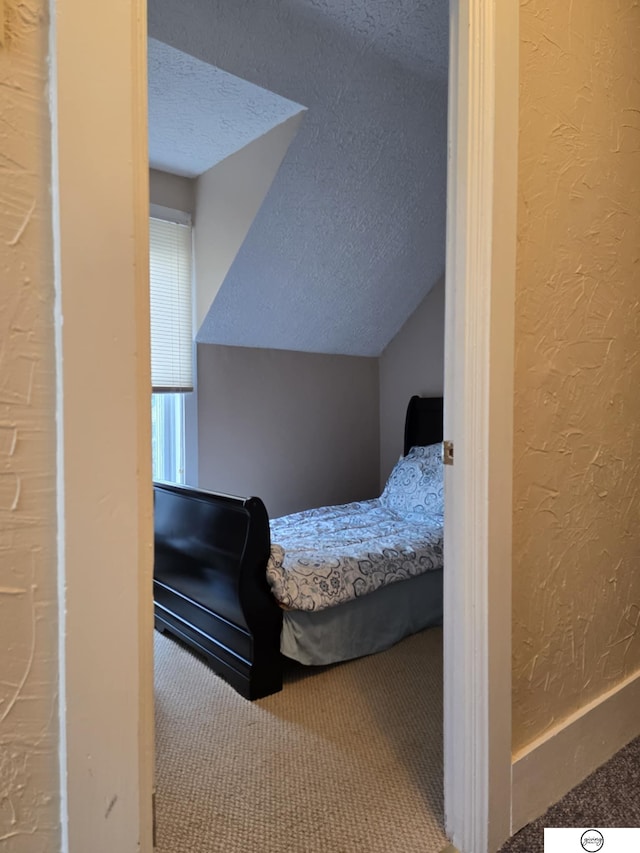 carpeted bedroom featuring a textured ceiling, vaulted ceiling, and a textured wall