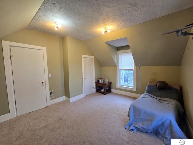 bedroom featuring visible vents, baseboards, vaulted ceiling, carpet flooring, and a textured ceiling